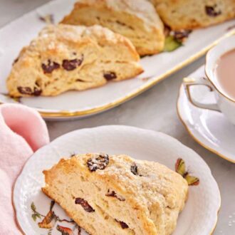 Pinterest graphic of a plate with a scone studded with dried cranberries with additional scones in the background.