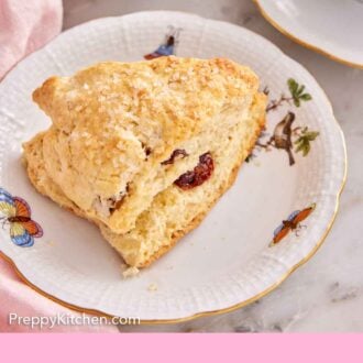 Pinterest graphic of a scone with dried cranberries inside on a plate.