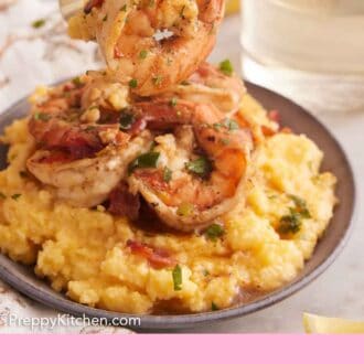 Pinterest graphic of a forkful of shrimp and grits lifted from a bowl with a glass of wine in the background.