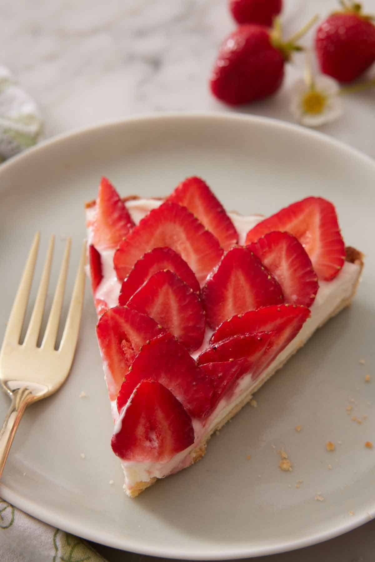 A plate with a slice of strawberry tart with a fork.