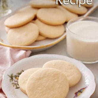 Pinterest graphic of a plate with three sugar cookies with a glass of milk and additional cookies on a platter in the background.