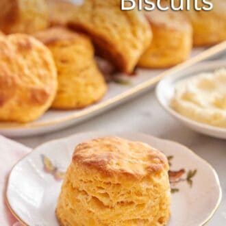 Pinterest graphic of a plate with a sweet potato biscuit with a plate of butter and platter of biscuits in the background.