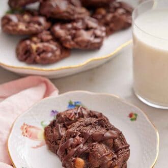 Pinterest graphic of a plate with two turtle cookies with a glass of milk and platter of cookies in the background.