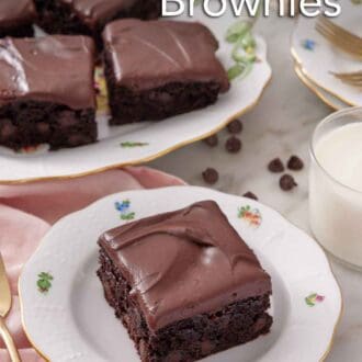 Pinterest graphic of a plate with a slice of zucchini brownie with a platter in the background. Glass of milk on the side.
