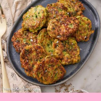 Pinterest graphic of an overhead view of a platter with a pile of zucchini fritters with green onions, sour cream, and blossom beside it.