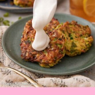 Pinterest graphic of sour cream spooned over a plate of zucchini fritters.