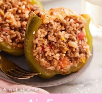 Pinterest graphic of a plate with an air fryer stuffed pepper cut in half, showing the interior packed with filling.