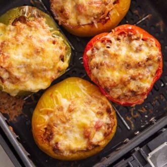 Overhead view of cooked stuffed peppers in an air fryer basket.