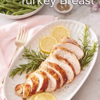 Pinterest graphic of a platter with a sliced air fryer turkey breast on top of rosemary and lemon slices. A plate of green beans in the background.