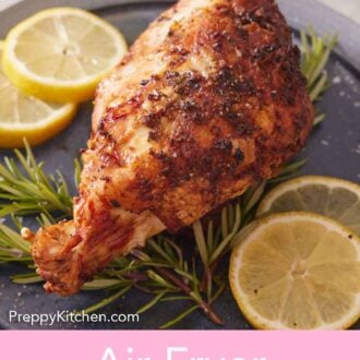 Pinterest graphic of a plate with an air fryer turkey breast on top of fresh rosemary and slices of lemon.
