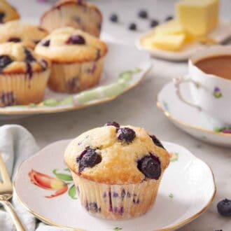 Pinterest graphic of a plate with a blueberry muffin with additional muffins in the background along with a cup of coffee and butter.