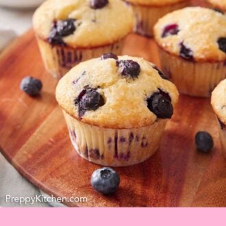 Pinterest graphic of a serving board with multiple blueberry muffins with some blueberries scattered around.