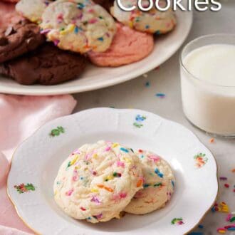 Pinterest graphic of a plate with two cake mix cookies with a glass of milk and additional cookies in the background.