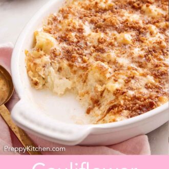 Pinterest graphic of a white baking dish of cauliflower gratin with a serving scooped out onto the plate in the background. Shredded cheese on a board in the back.