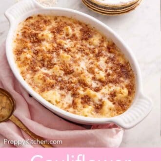 Pinterest graphic of a baking dish of cauliflower gratin with a stack of plates and forks in the background.