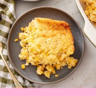 Pinterest graphic of overhead view of two plates with corn casserole. One plate with a fork.
