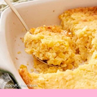 Pinterest graphic of a spoonful of corn casserole in the corner of a baking dish, getting scooped.