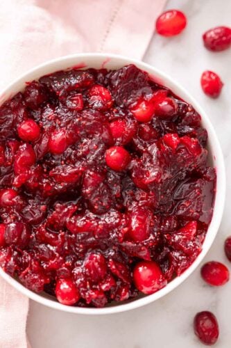 Overhead view of a bowl of cranberry sauce with pieces of whole cranberries.