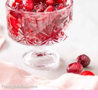 Pinterest graphic of a glass bowl of cranberry sauce with some cranberries off to the side.