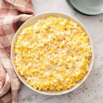 Overhead view of a bowl of creamed corn with black pepper.