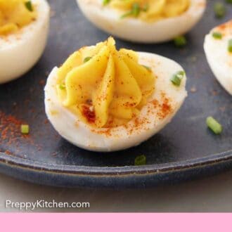 Pinterest graphic of a plate with deviled eggs topped with chives and paprika.
