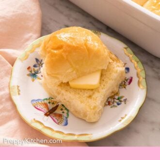 Pinterest graphic of a plate with a dinner roll, sliced, with a piece of butter placed in between. A baking dish with more rolls in the background.