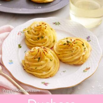 Pinterest graphic of a plate with three duchess potatoes topped with parsley and flaky salt and a glass of wine in the background along with a platter.