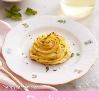 Pinterest graphic of a plate with a serving of duchess potatoes topped with parsley and flaky salt. A glass of wine and bowl of sour cream in the background.