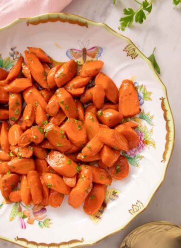 Overhead view of a plate of glazed carrots with chopped parsley garnish.