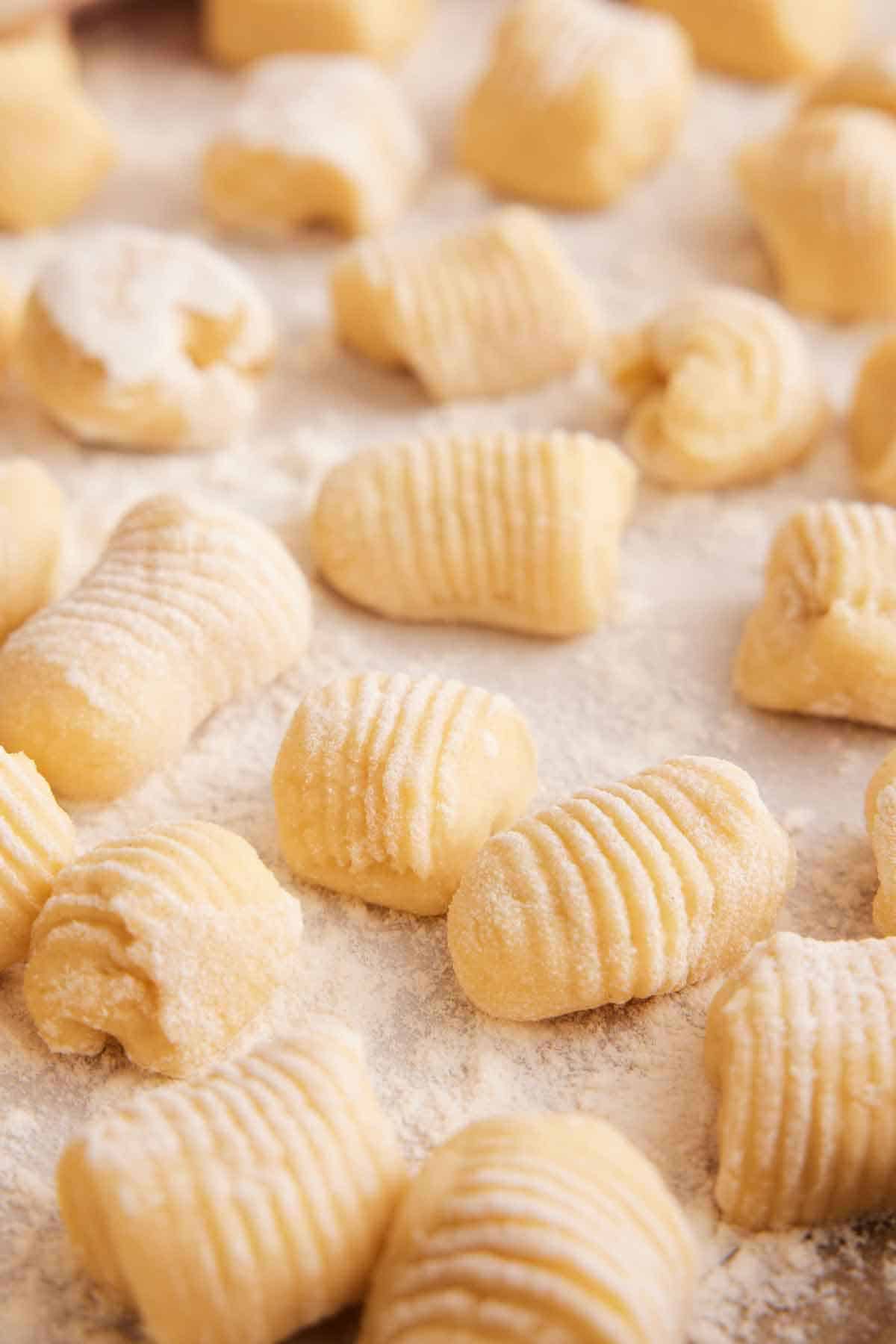 Multiple pieces of rolled gnocchi dough coated in a light layer of flour.
