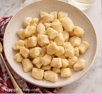 Pinterest graphic of a plate of gnocchi with a glass of wine in the background.
