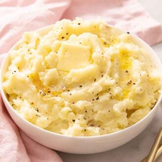 A bowl of mashed potatoes with pepper, melted butter, and a pat of butte ron top.