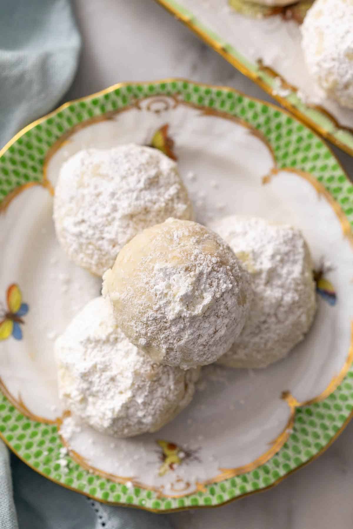 Overhead view of a small pile of Mexican wedding cookies on a small plate.
