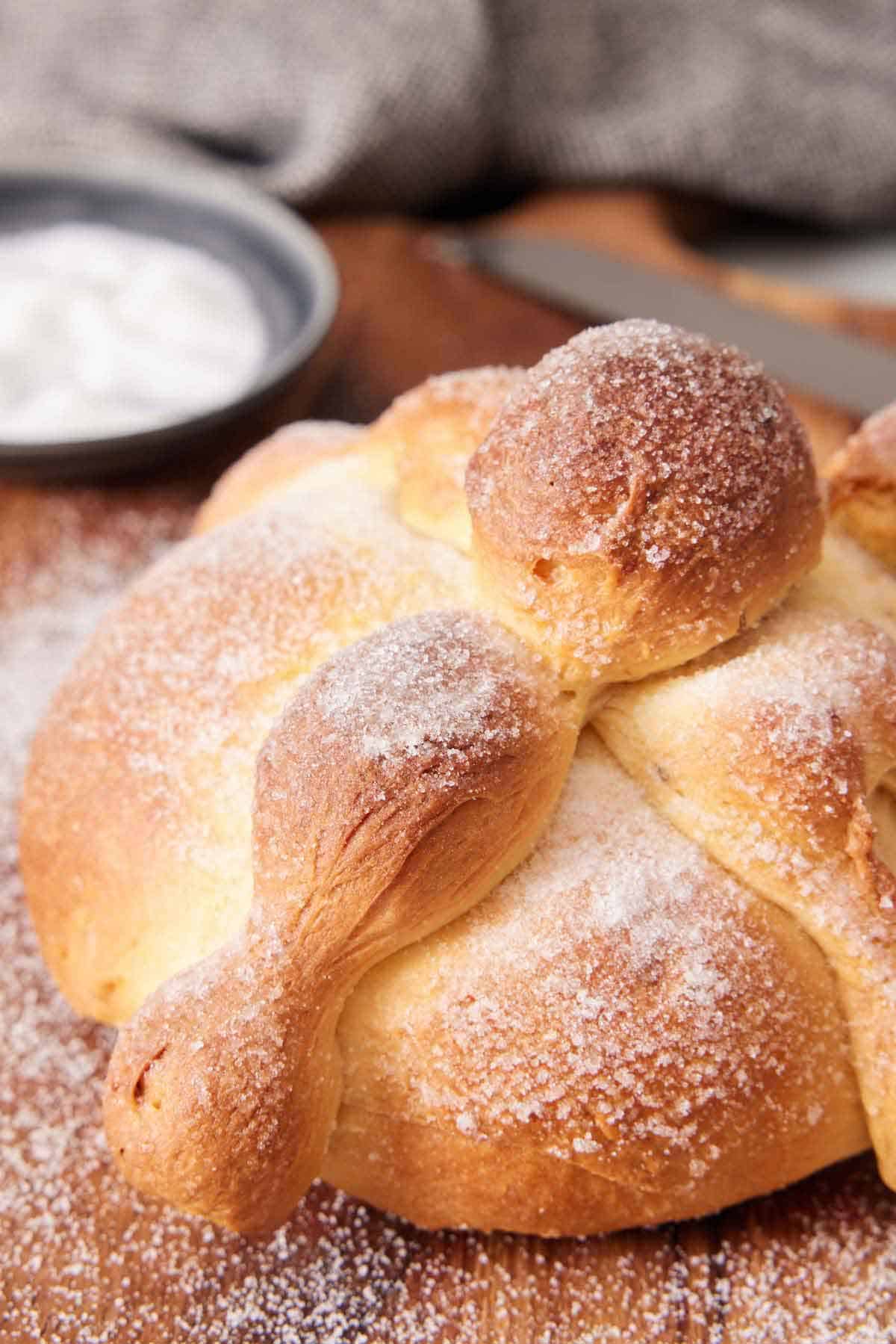 A close up view of Pan de Muerto topped with a sprinkling of sugar.