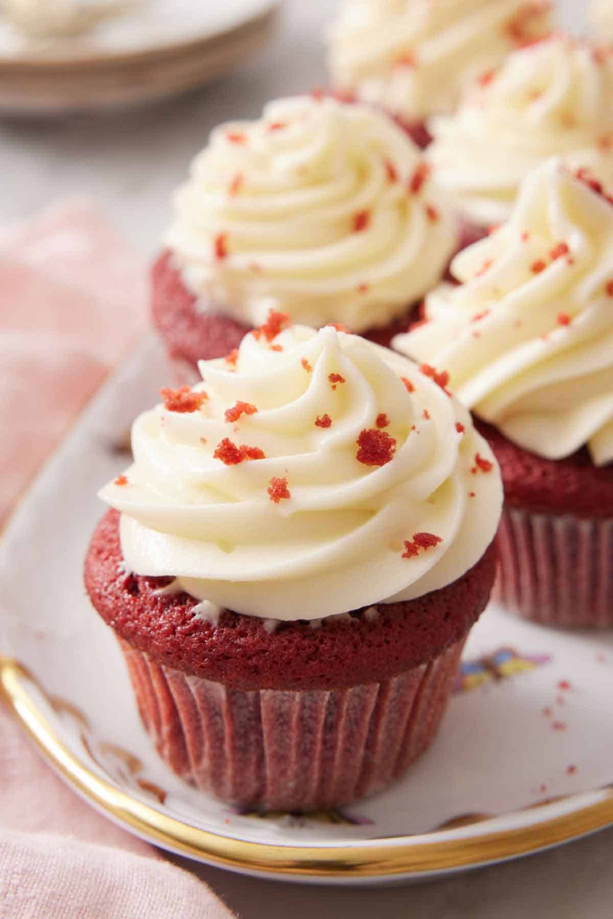 A platter of red velvet cupcakes with one in focus in the front.