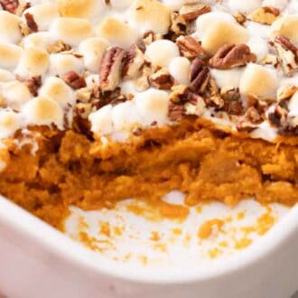 A close up view of a baking dish of sweet potato casserole with a serving scooped out.