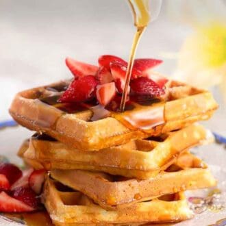 Pinterest graphic of a stack of waffles and strawberries with syrup poured over top.