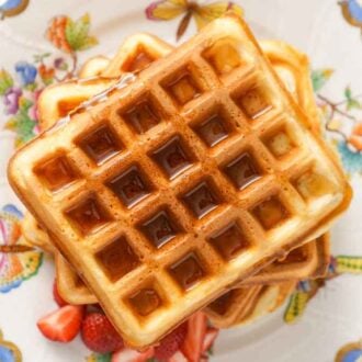 Overhead view of a stack of waffles with syrup on top.