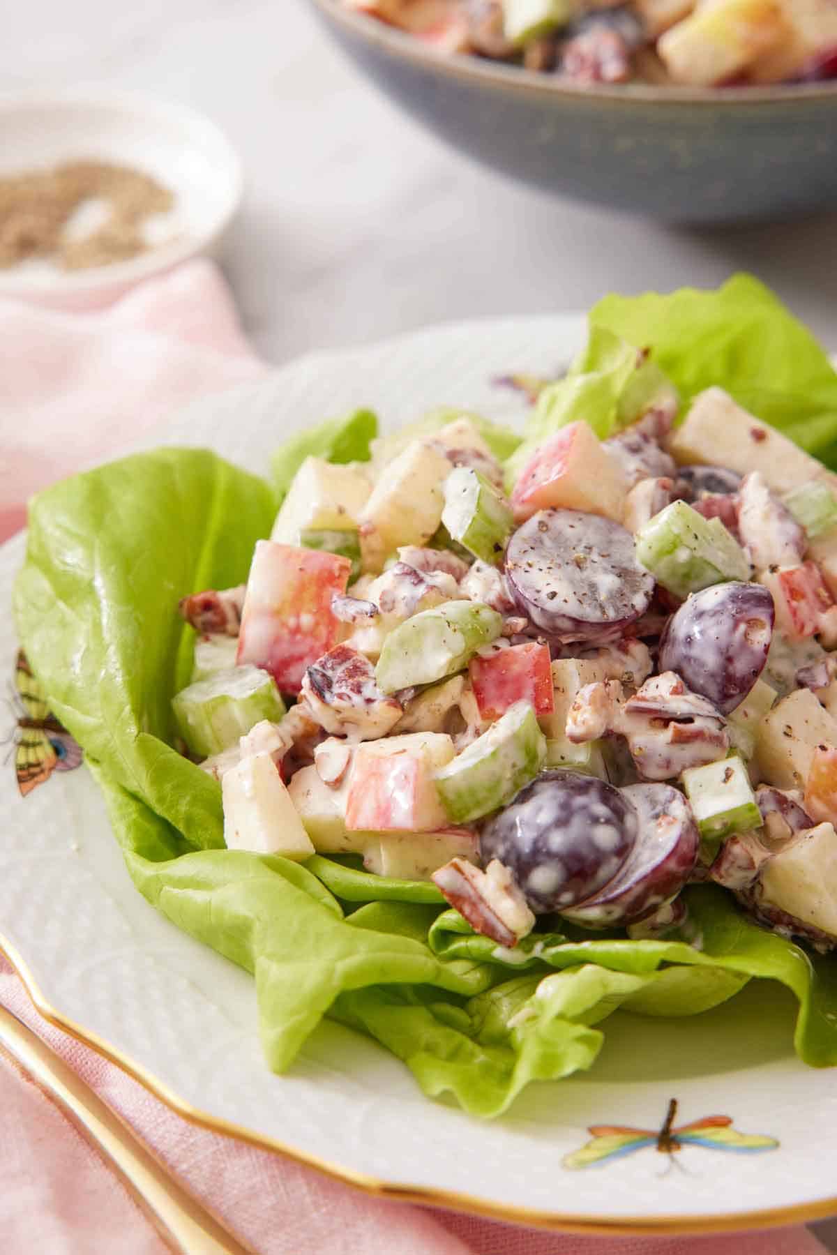 A plate with a serving of Waldorf salad over lettuce.