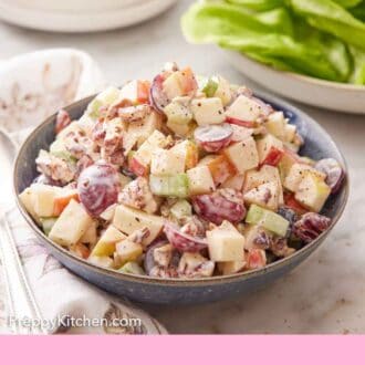 Pinterest graphic of a bowl of Waldorf salad with lettuce and a stack of plates in the background.