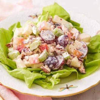 A plate with Waldorf salad over lettuce.
