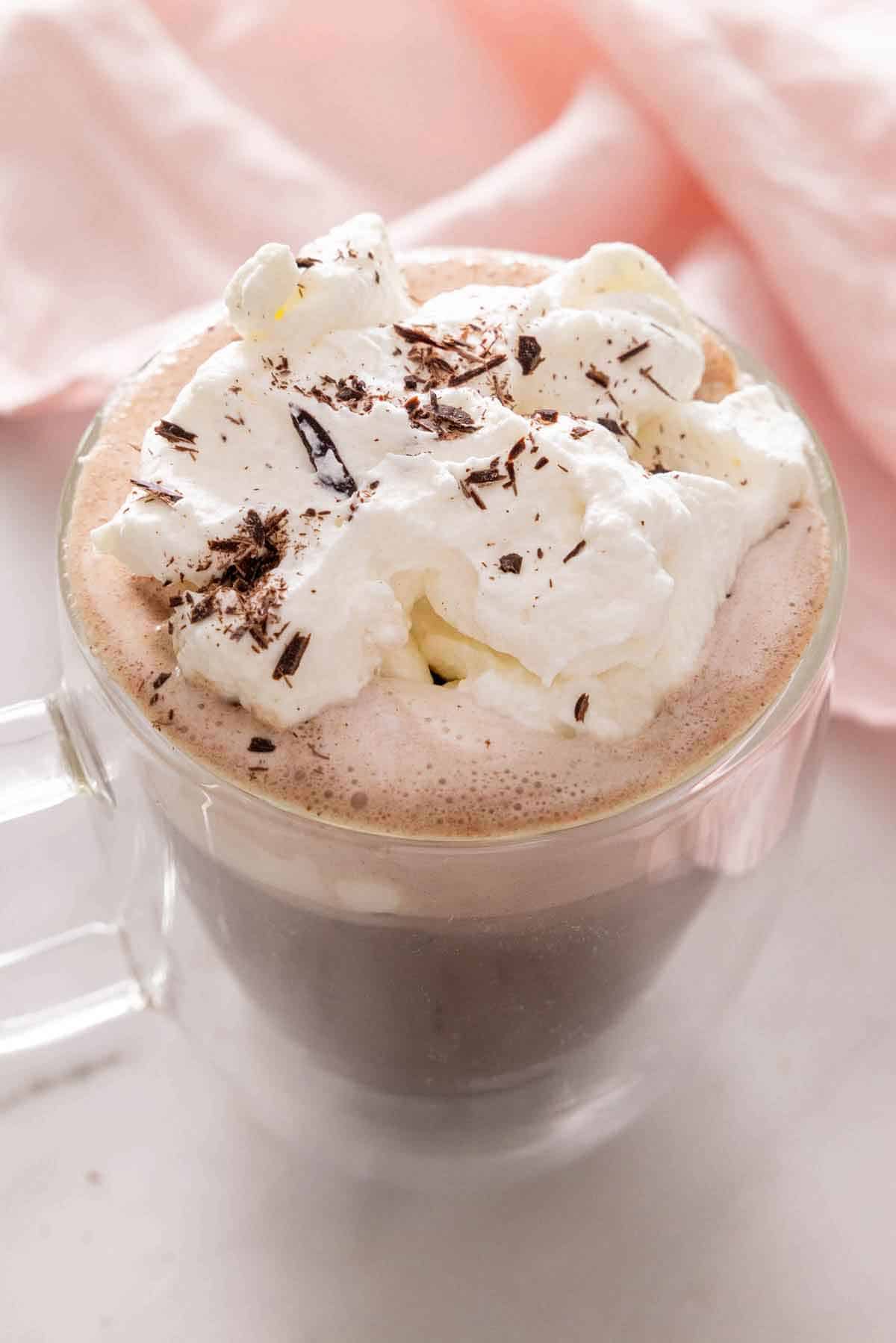 A cup of hot chocolate with whipped cream and shaved chocolate on top.