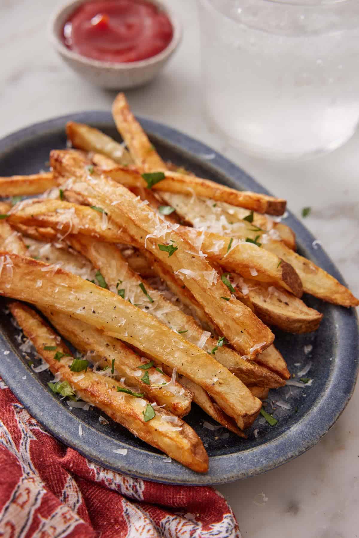 A plate with air fryer french fries garnished with parsley and parmesan.