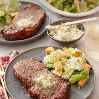 Pinterest graphic of a plate with an air fryer steak with a side of salad. An additional plated serving in the background along with a platter of salad and herb butter.