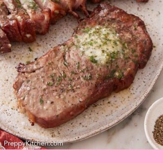 Pinterest graphic of a plate with one whole air fryer steak with a second one beside it, fully sliced.