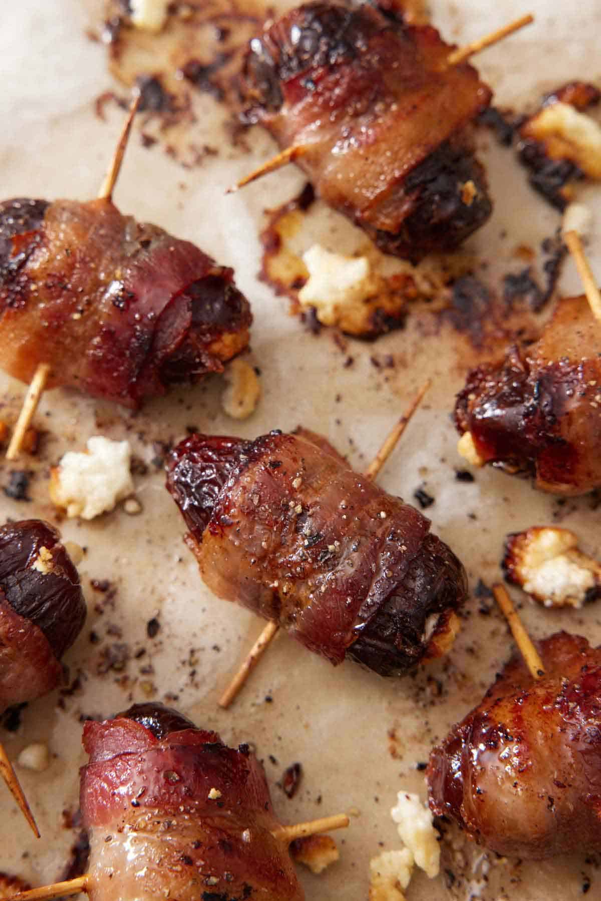 Overhead view of bacon wrapped dates freshly out of the oven on a lined sheet pan.
