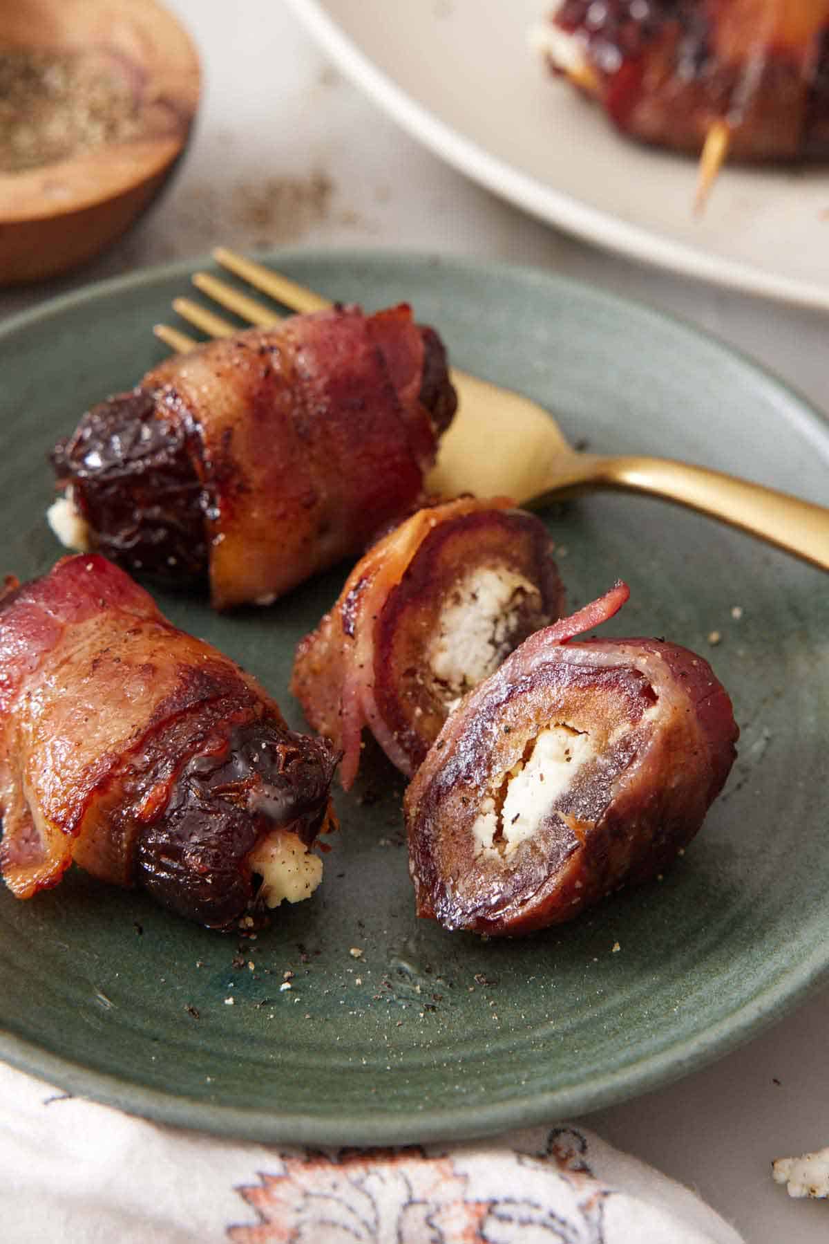 A plate with bacon wrapped dates with one cut in half.