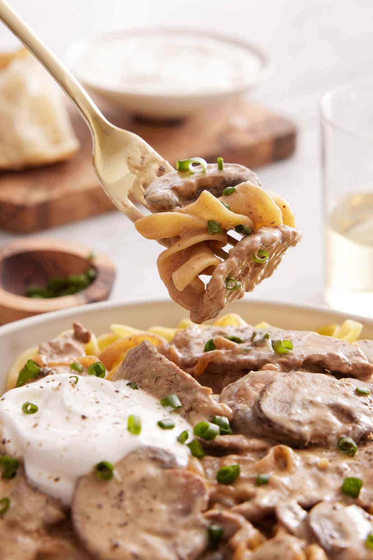A forkful of beef stroganoff lifted from a bowl.