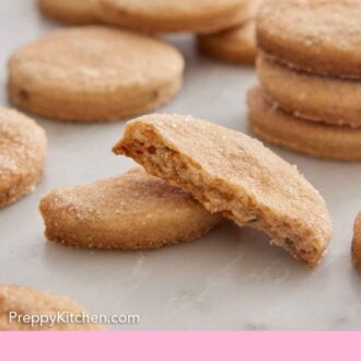 Pinterest graphic of a biscochito broken in half, showing the interior. More cookies in the background.