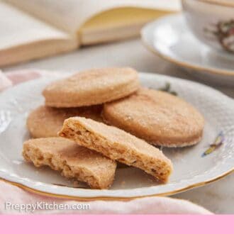Pinterest graphic of a plate with some biscochitos, the one in front broken in half, showing the interior.